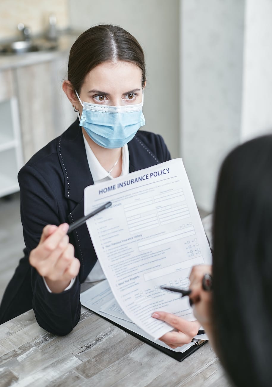 Insurance agent 5 a woman wearing face mask holding a home insurance policy